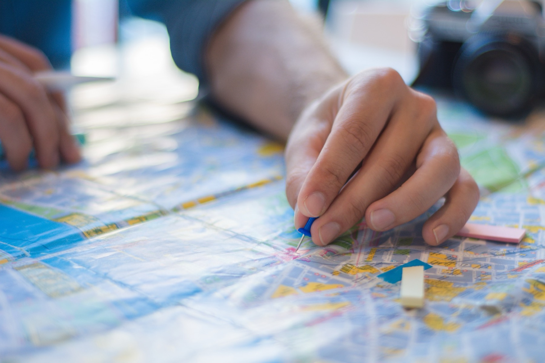 Someone sits at a desk, looking over a map and pinning places to chart out a course forward.